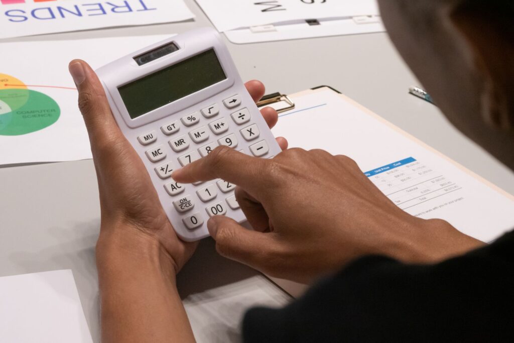 Persona usando calculadora entre documentos y gráficos financieros
